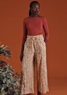 Model wears peachy floral print on cream base cotton wide leg lightweight cotton pants with elastic at back of waistband and drawstring and pockets | Karma East Australia