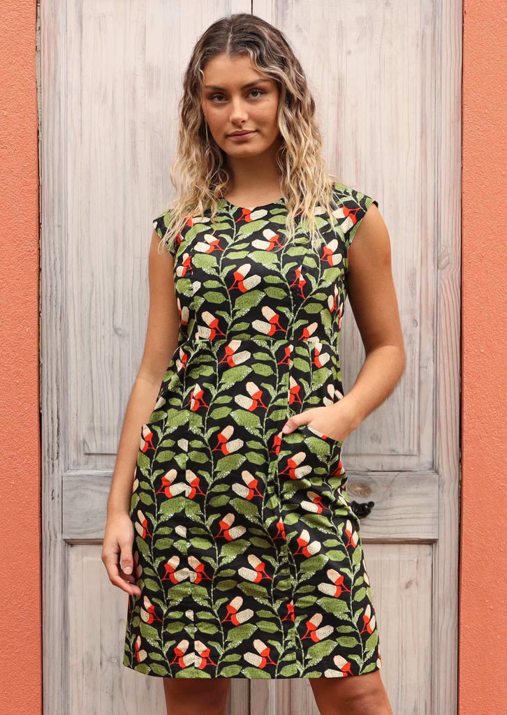 Model wears Kari Dress Oak green and black print cotton high neck dress with cap raglan sleeves, back zip and pockets 