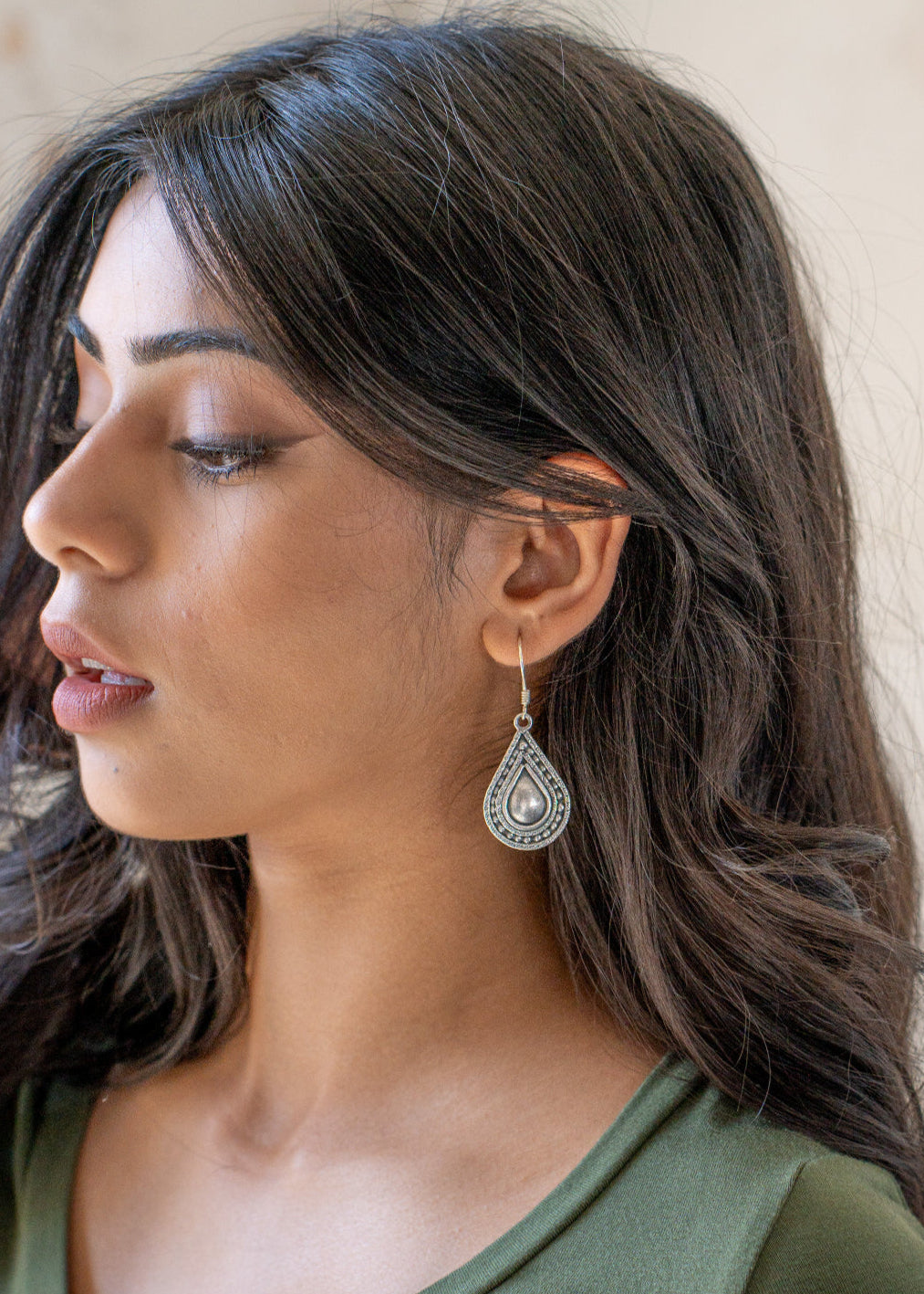 Woman wearing a Hill Tribe Silver Tear 
 Drop shaped earring with a beige background