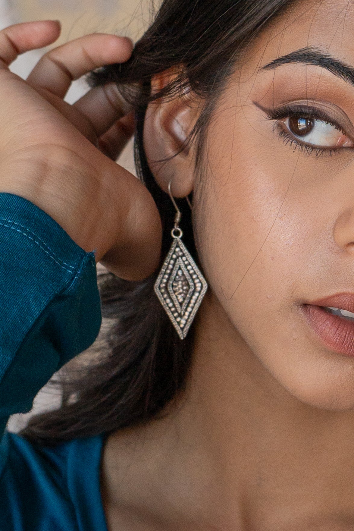 Close-up of a woman adjusting her hair over her ear wearing Hill Tribe Silver Diamond earring