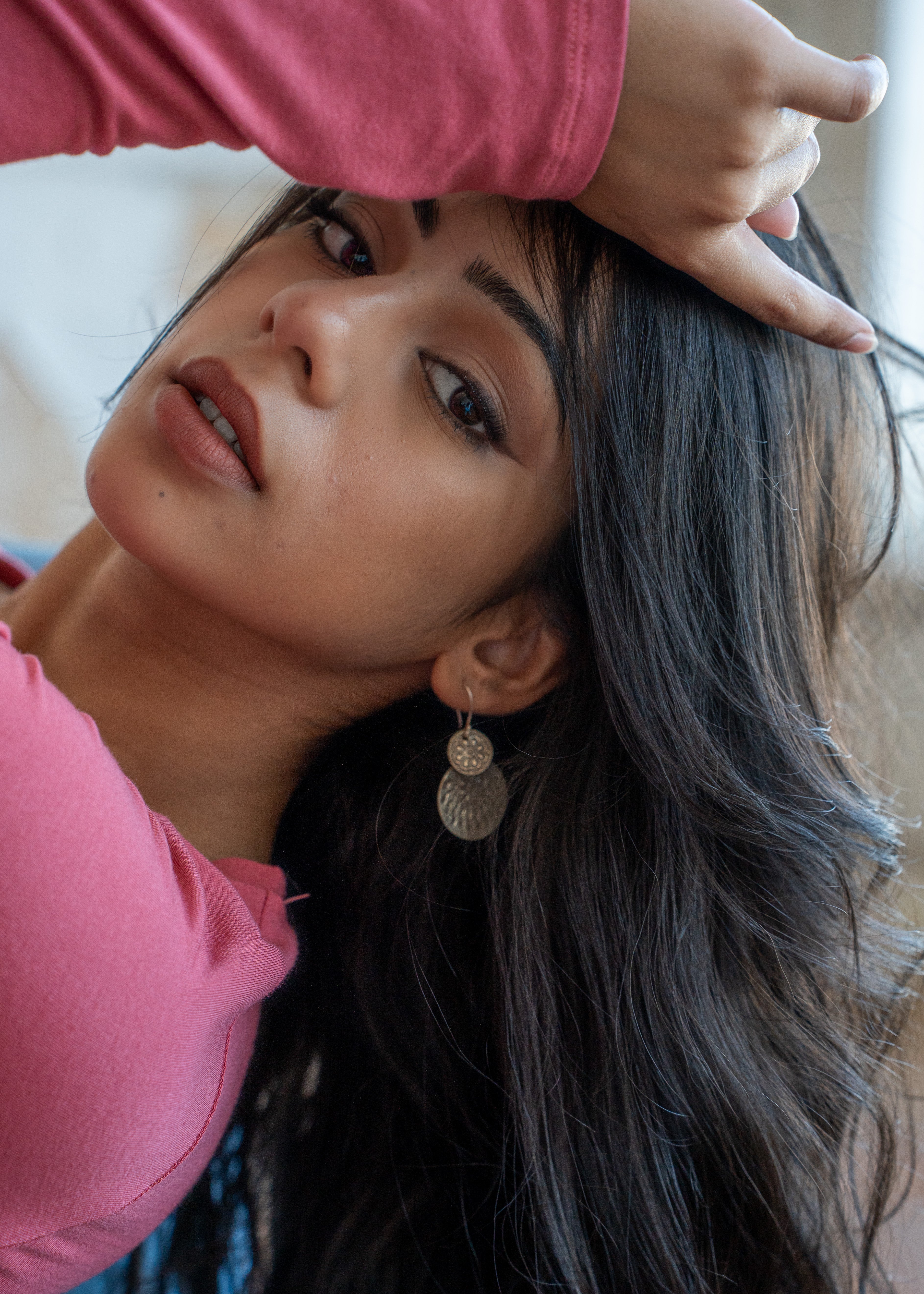 Woman with long dark hair wearing large silver hill tribe earrings, with a blurred background