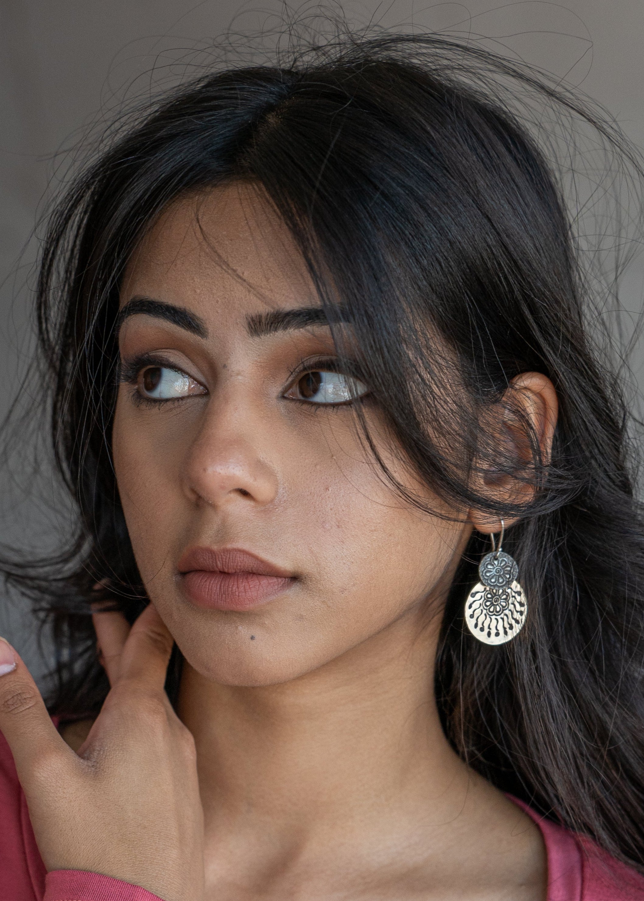Woman wearing a large sliver hill tribe earring with a neutral background
