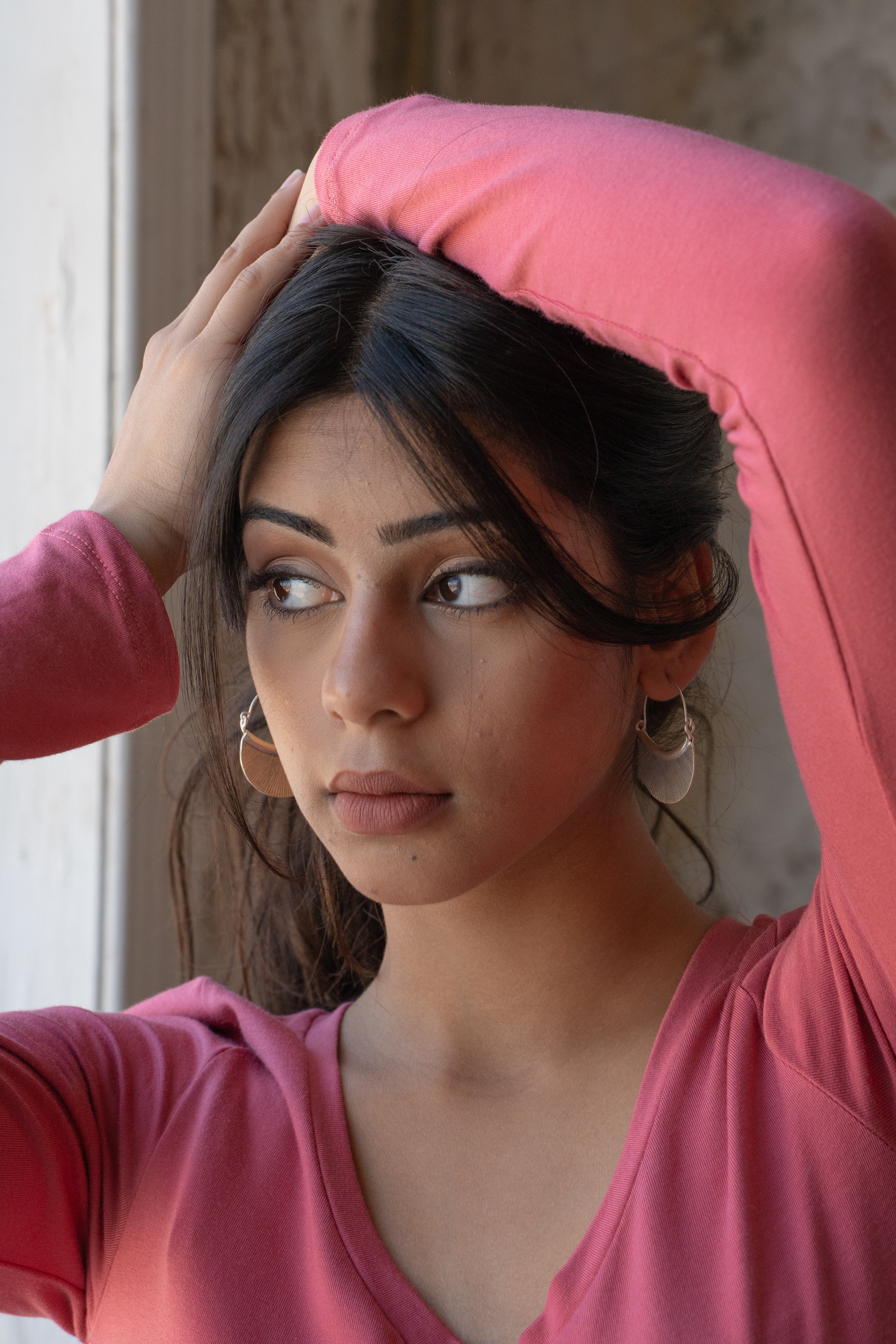 Woman with dark hair in a pink top, modelling Hill Tribe Silver earrings