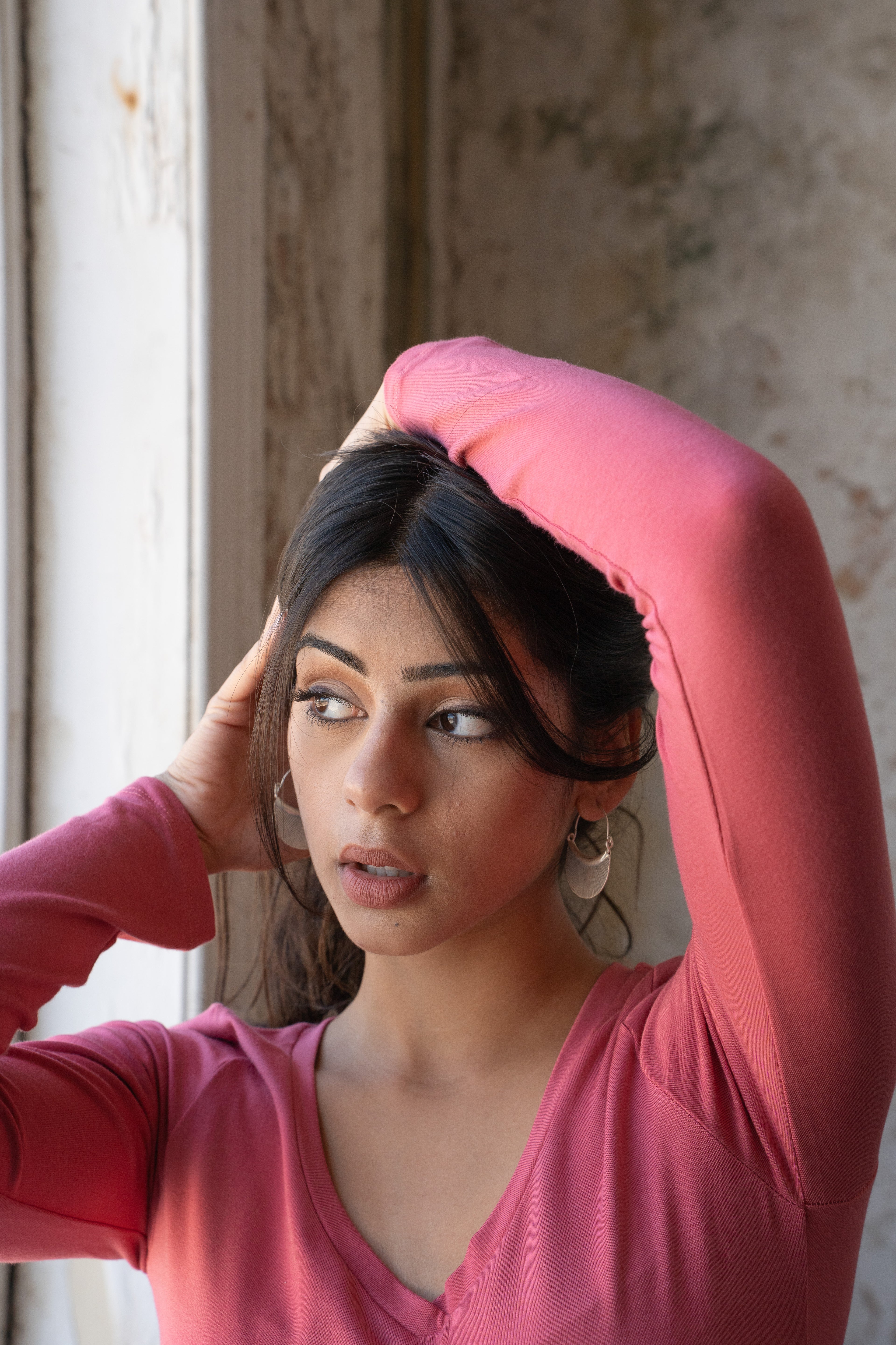 Woman in a pink shirt with one arm raised, wearing Hill Tribe Silver earrings 
