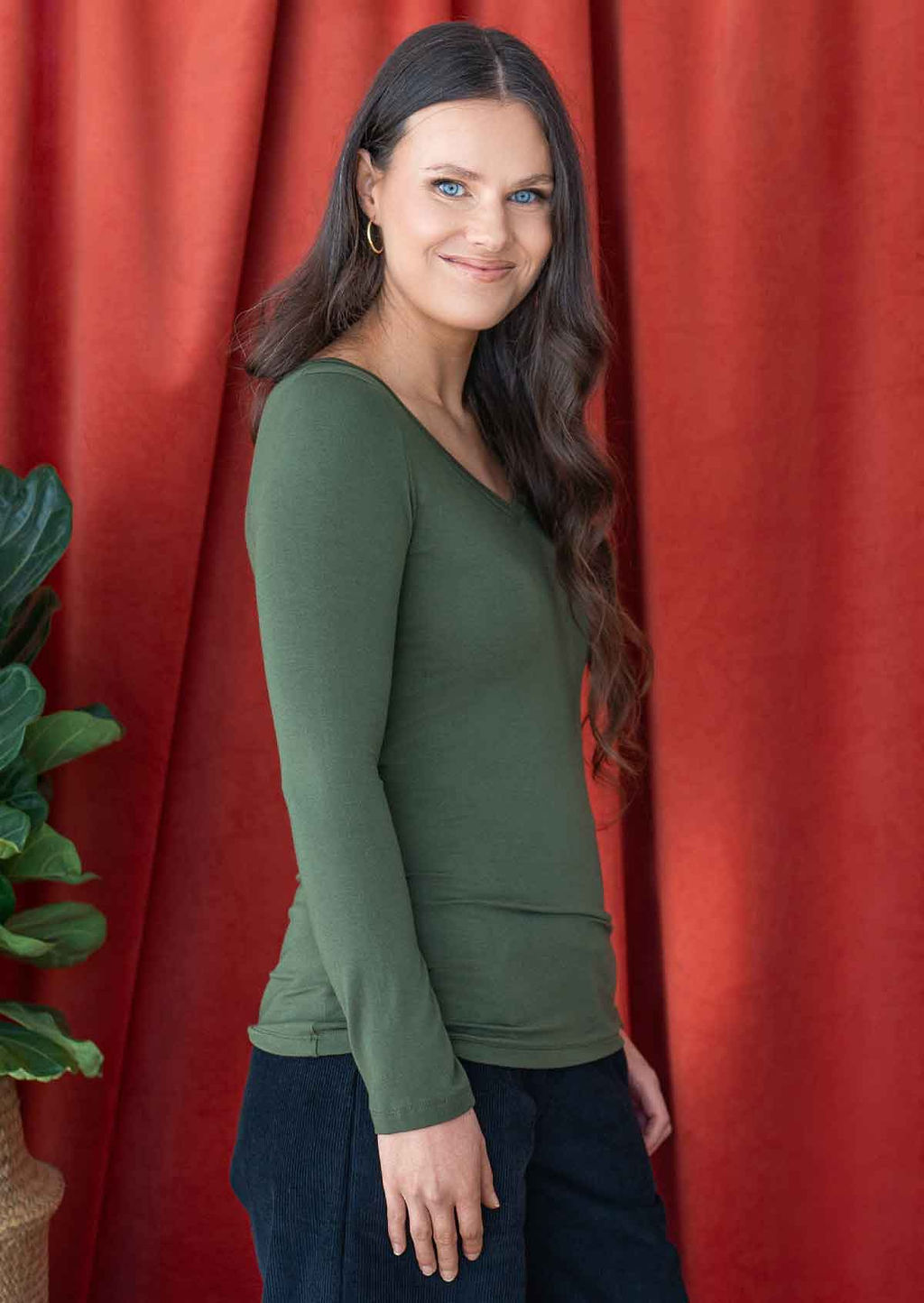 woman wearing long sleeve stretch rayon jersey top in green with v-neck over black corduroy pants 
