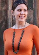 Model wears necklace with black beads.