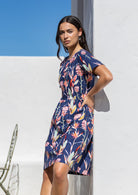 Woman posing in a relaxed fit navy floral dress with button clasp at the back.