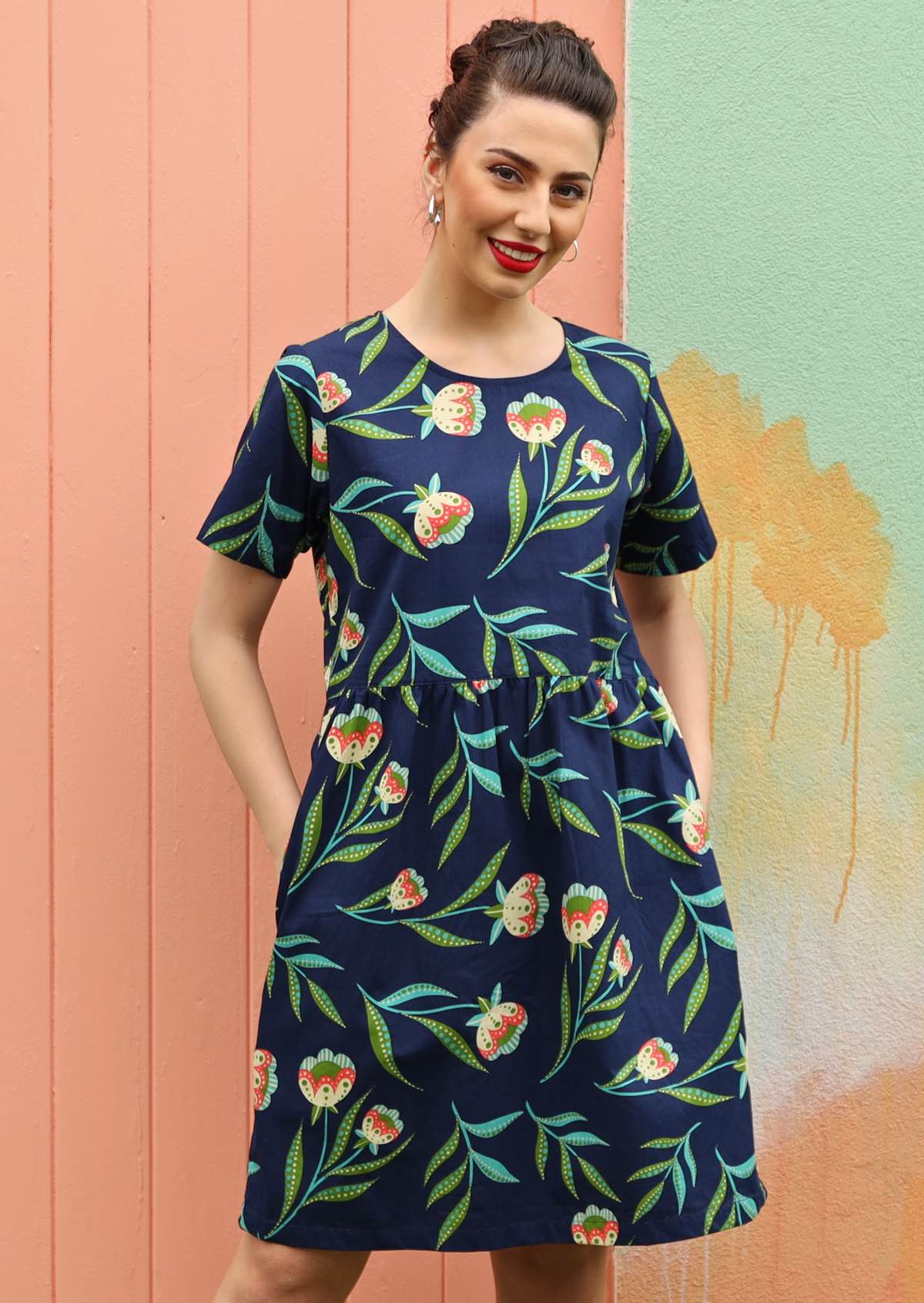 Model wears a navy dress with a floral pattern. 