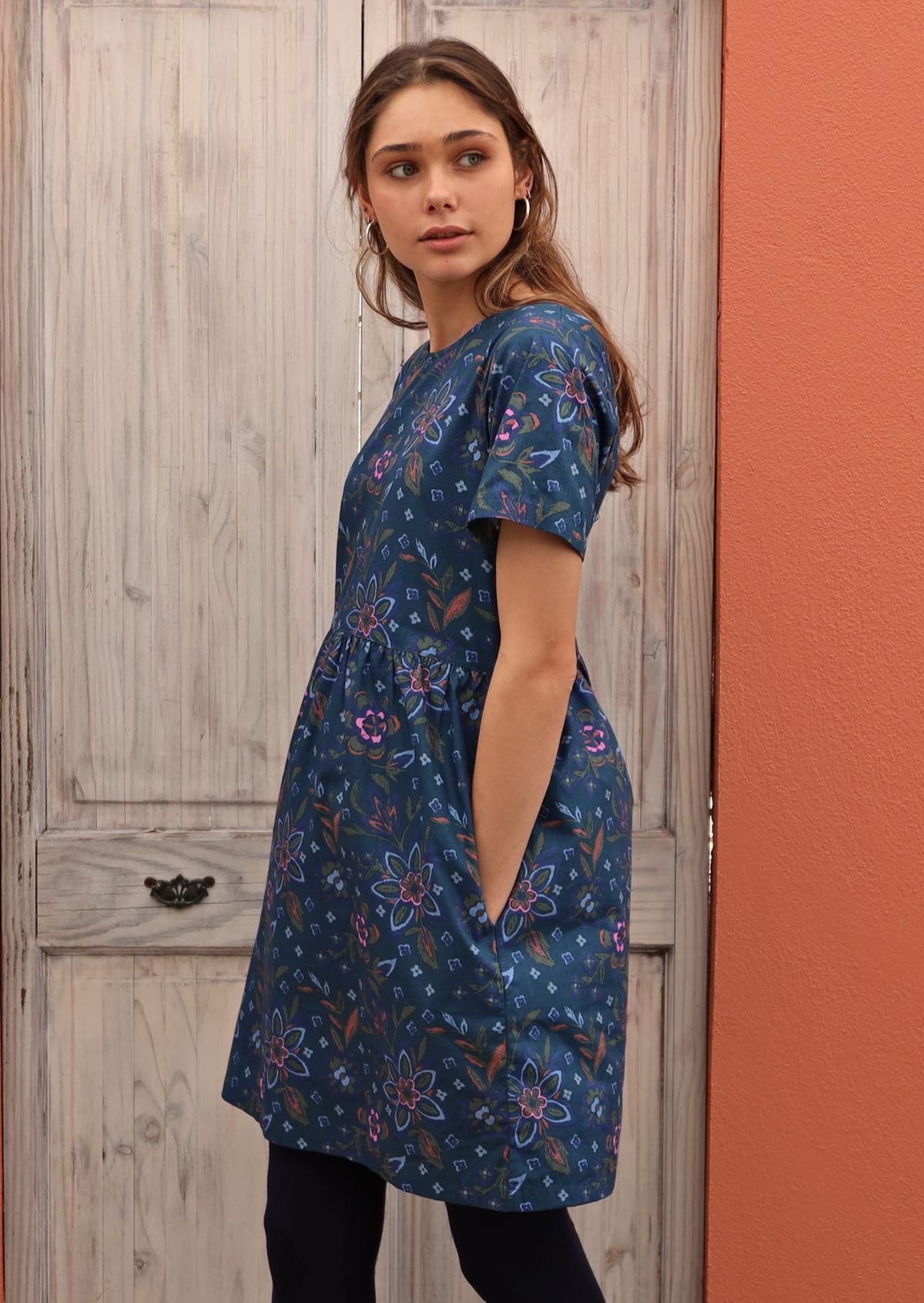Model has her hands in the pockets of her relaxed fit 100% cotton dress. 