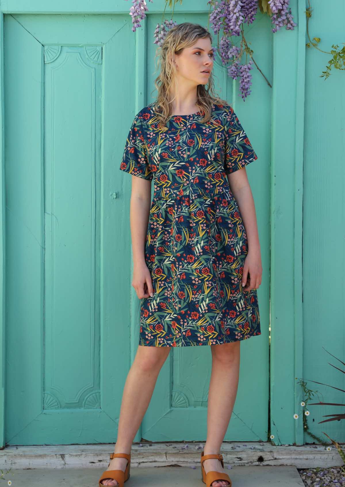 Model wears short sleeve floral dress styled with sandals. 