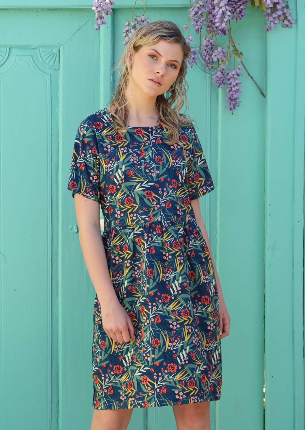 Blonde woman wears a loose fitting dress with small pin tucks. 
