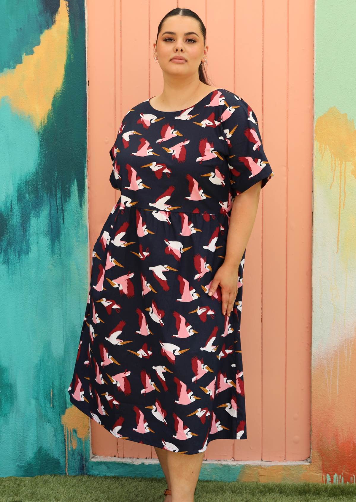 Curve model wears below knee navy blue cotton dress with fun bird print 