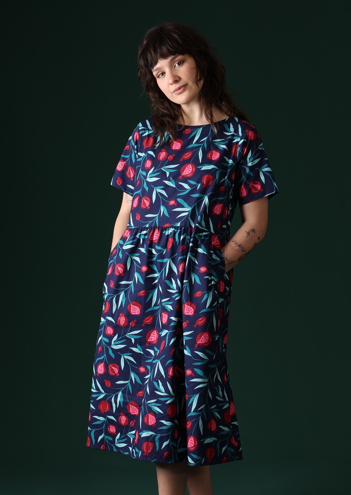 Model wears 100% cotton dress with fruit print on blue base 