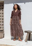 Woman wearing an Indian Cotton maxi dress standing against a white wall with hands in pockets 