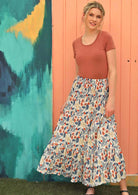 Model wears a boho style maxi skirt with a floral print. 