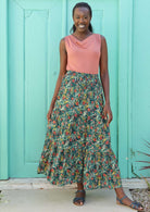 Model wears a skirt with a colourful floral print on a green base.