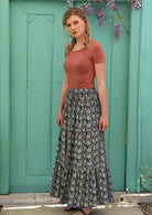 Model stands on her side to show the volume of her long skirt. 