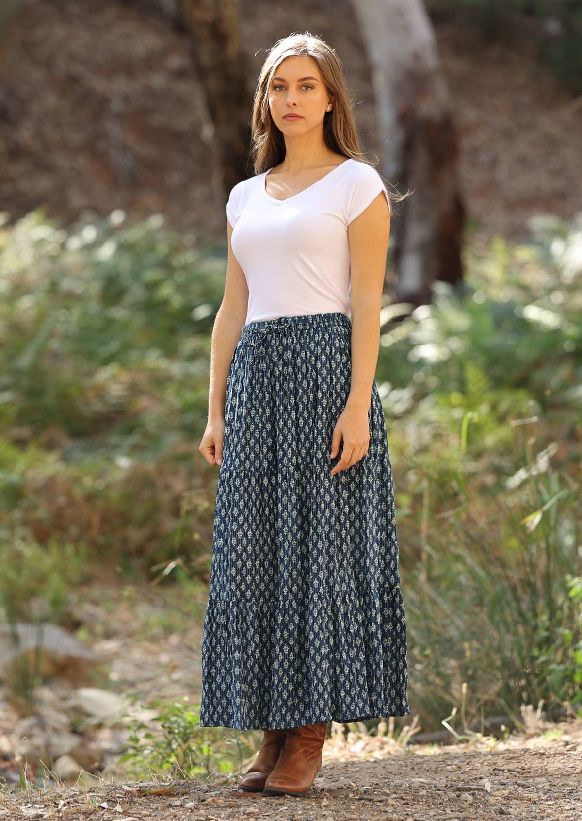 Blue floral maxi skirt is styled with a white top and brown boots. 