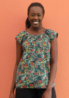 Model wears a floral top with a smocked chest. 