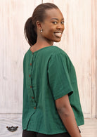 Model wears green cotton gauze top with decorative buttons down the back