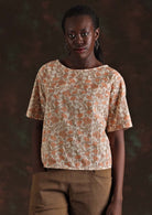Model wears peachy pink floral print on cream base cotton top