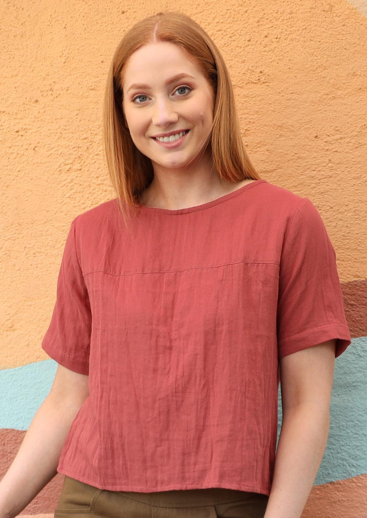 Model wears 100% cotton dress in a peachy terracotta colour. 