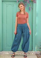 Blonde woman pairs lightweight boho pants with sandals and a short sleeve top. 