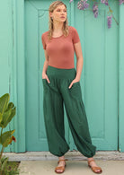 Blonde model wears 100% cotton green boho style pants with pockets. 