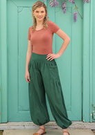 Model pairs loose fitting green pants with a short sleeve top. 