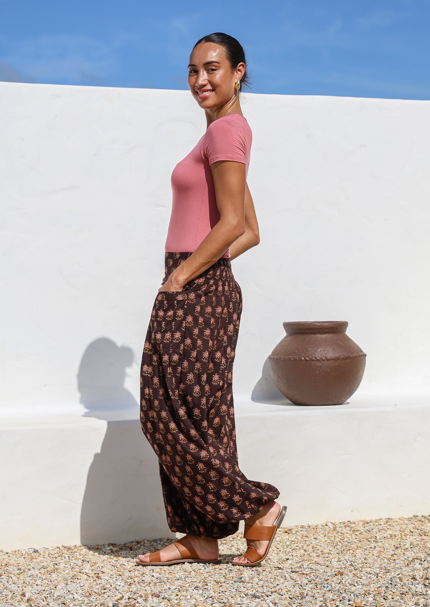 Side pose of model wearing 100% cotton harem pants with wide flat front waistband  elasticated ankles and pockets.