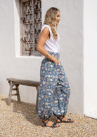 Side pose of model wearing a floral cotton pants with elastic ankles and waist.