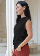 Woman wearing a black sleeveless stretch rayon top and rust pants