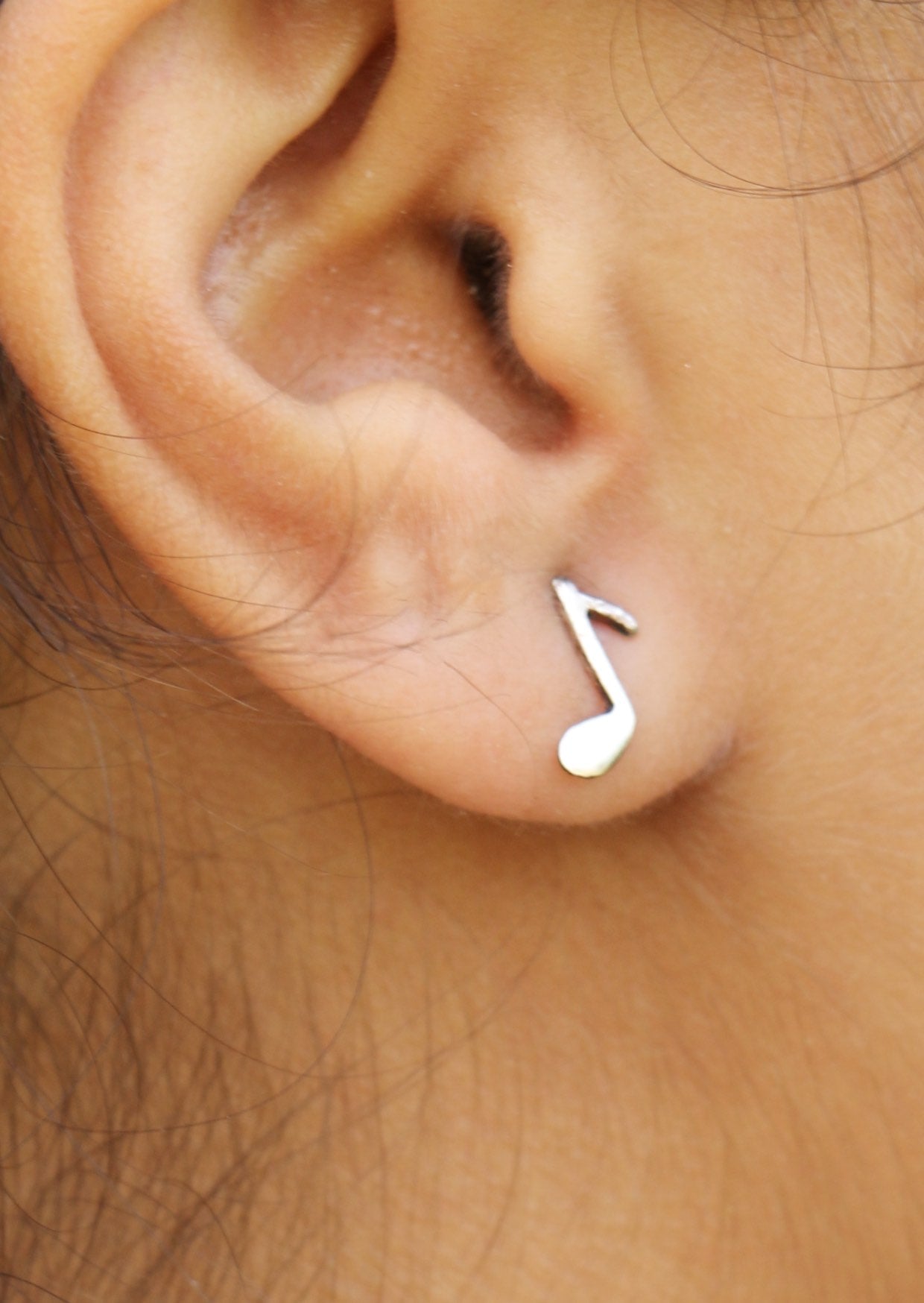 Woman wearing lovely small silver Quaver studs showcasing musical eight note 
