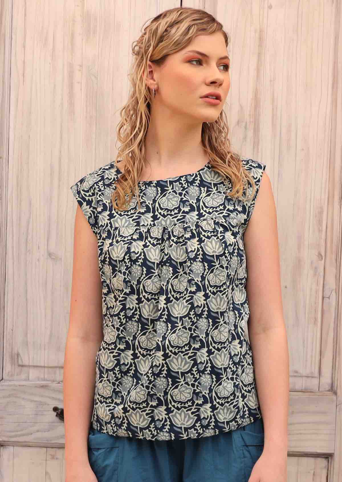 Blonde model wears a loose fit top with small gathers under the neckline.
