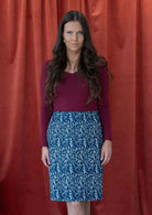 Model pairs a midlength, reversible cotton skirt with long sleeve maroon top.