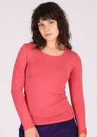 Woman wearing a round neck pink long sleeve rayon top.