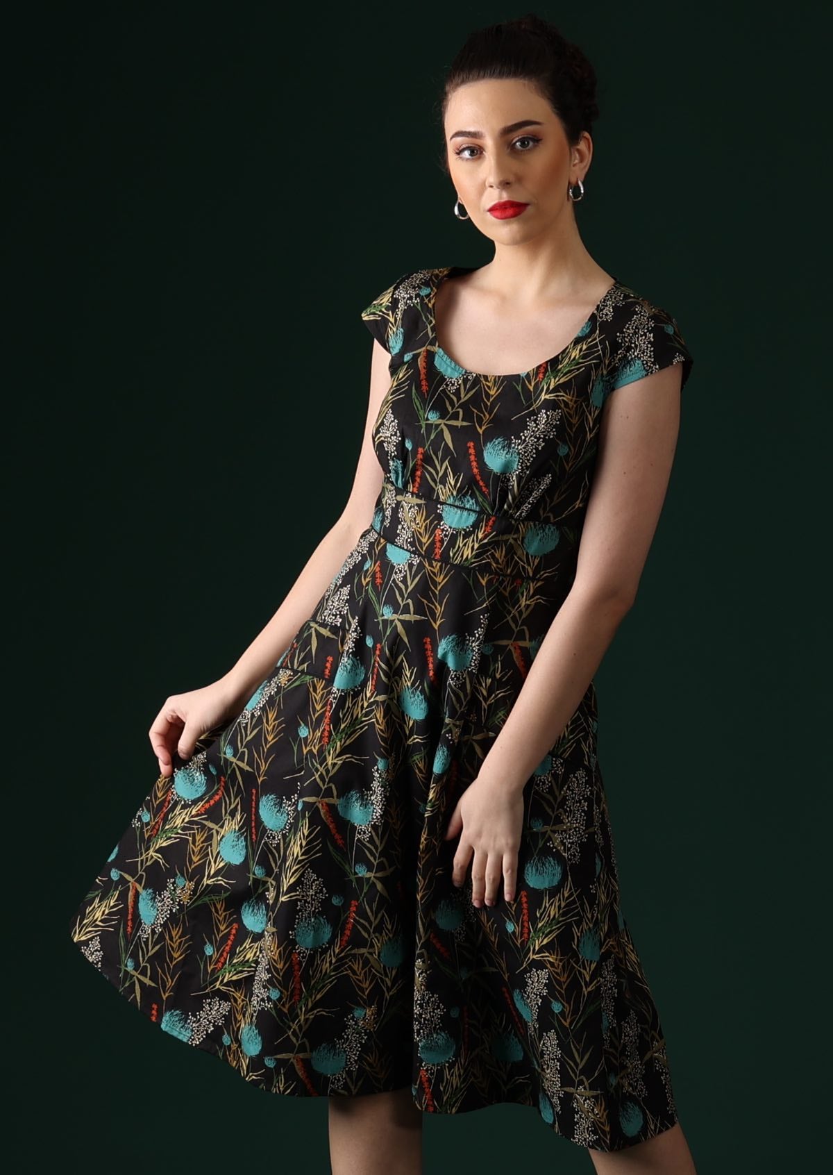 Model wears Scarlett Dress Thistle botanical print on black cotton retro inspired dress with cap sleeves, round neckline, central back zip and fuller skirt with pockets | Karma East Australia