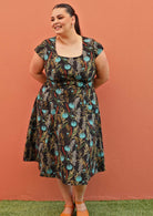 Plus size model wearing retro style cotton dress in black and teal with pockets