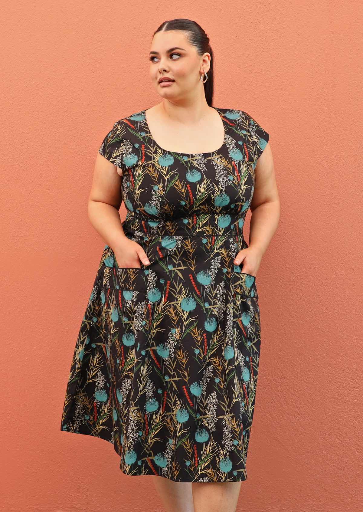 Plus size model wearing retro style cotton dress in black and teal with scoop neck