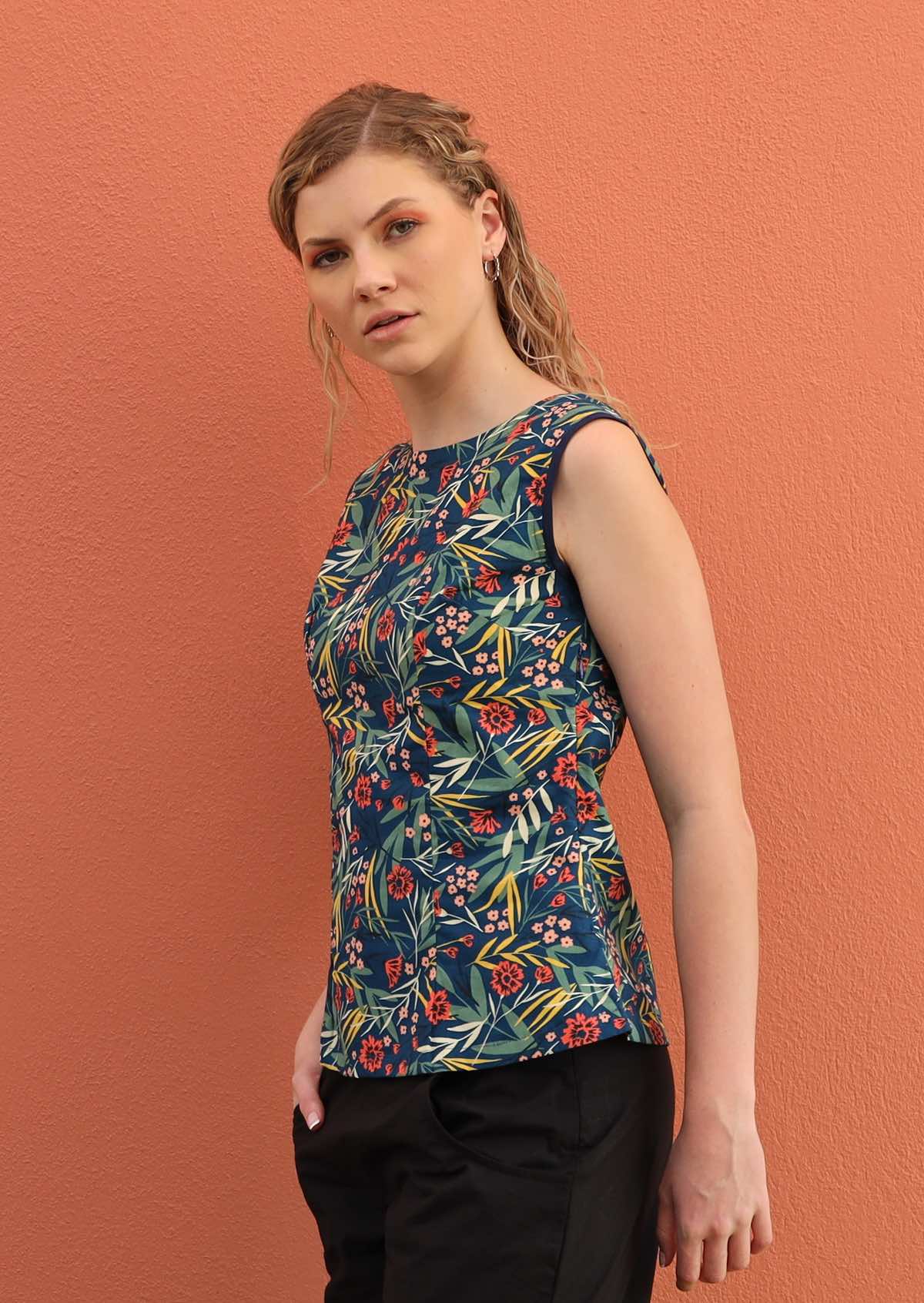 Blonde model wears a tailored top with plain trim around the arms. 
