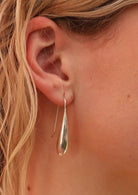 close up of woman's ear with oblong silver drop earring