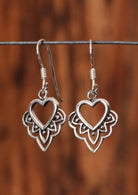 92.5% silver boho heart earrings sit on a wire for display