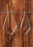 92.5% silver angular droplet earrings hanging on a wire for display.