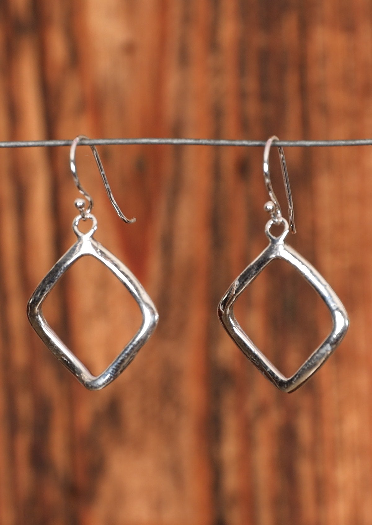 92.5% silver dangly diamond earrings sitting on wire for display.