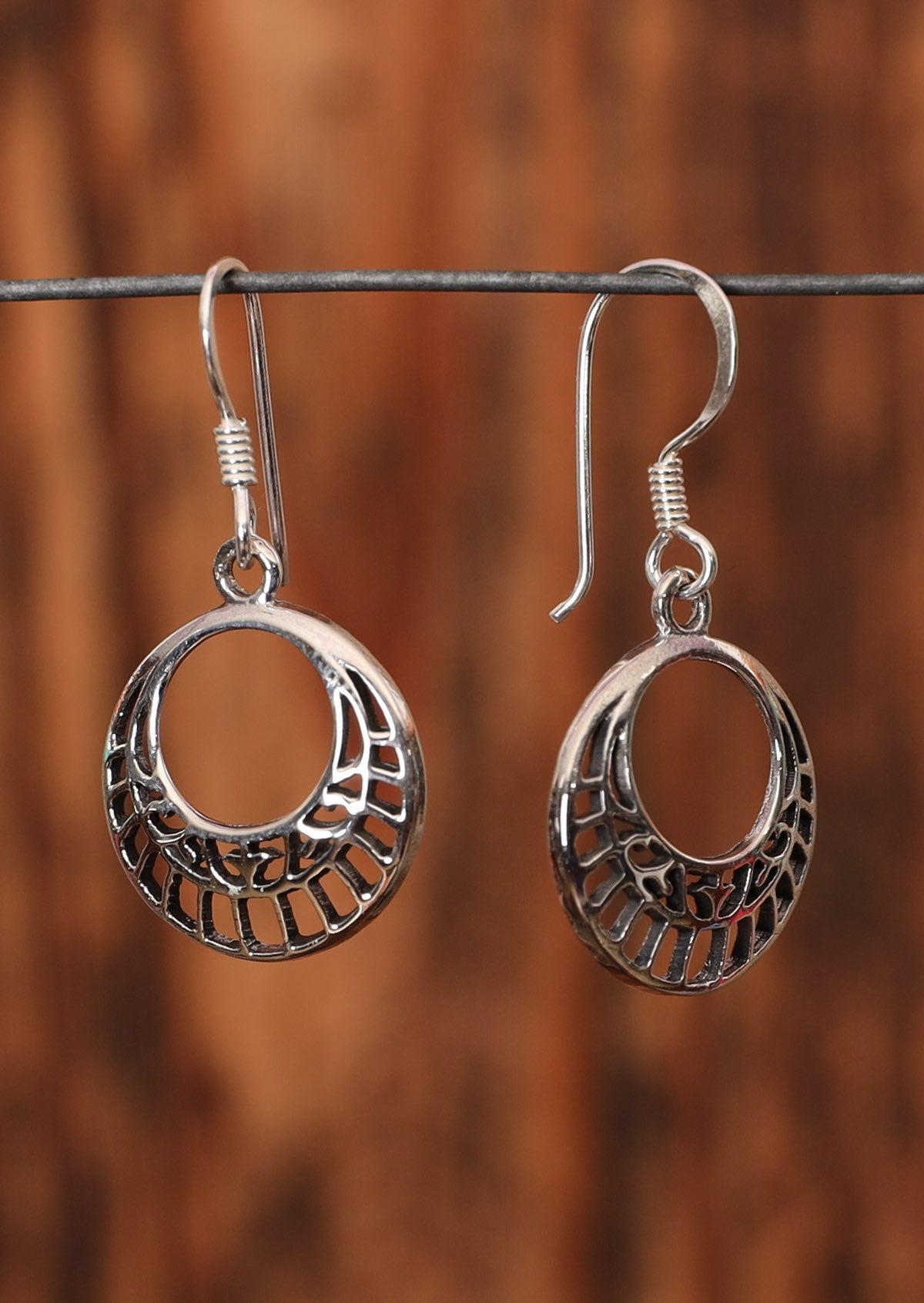 92.5% silver disk earrings with pattern sit on a wire for display.