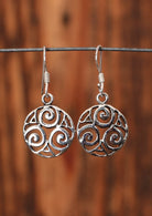 92.5% silver encircled triskele earrings hanging on a wire for display.