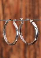 92.5% silver hoop earrings with a gentle edge sitting on a wire for display.