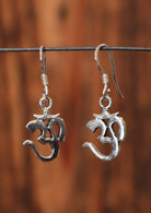 92.5% silver Om symbol earrings hanging from a wire for display.