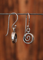 92.5% silver wave earrings sit on a wire for display.