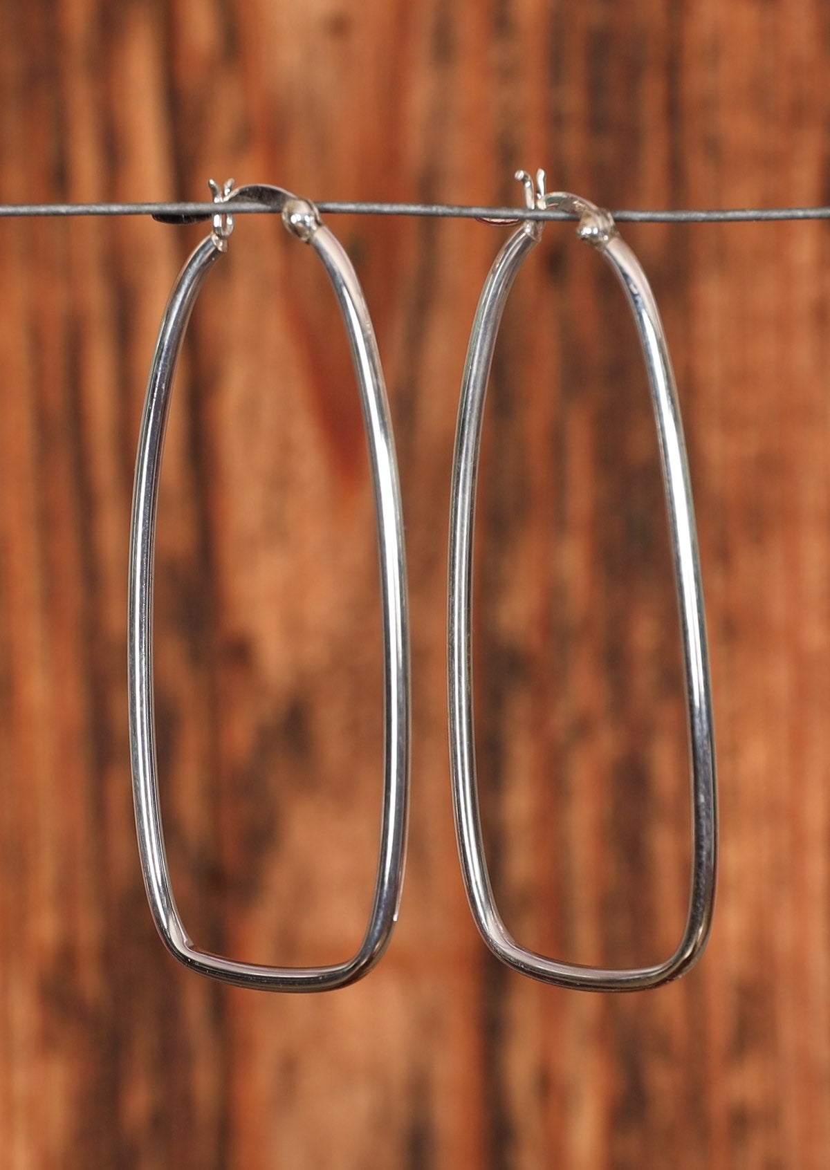 92.5%  stretched silver hoop earrings sitting on a wire for display